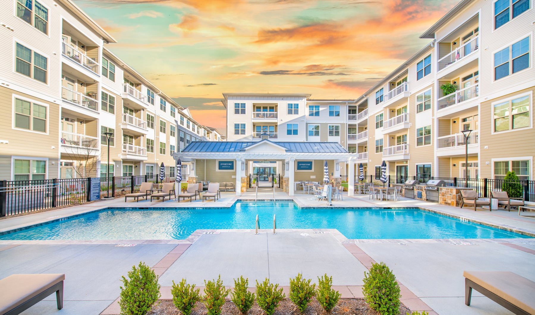 Large sparkling blue pool with a large deck and lounge chairs 