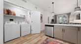 laundry closet with side-by-side washer/dryer units next to kitchen