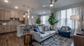 a living room with a couch and chairs open to kitchen