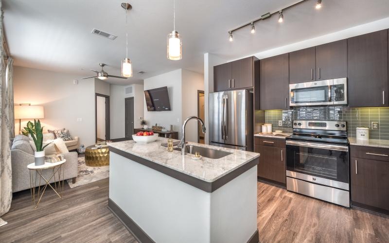 Spacious and well lit kitchen with wood floors and stainless steel appliances