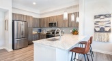 Spacious and well lit kitchen with stainless steel appliances and dark accents 