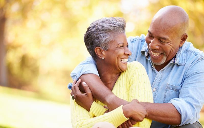 a man and woman hug in a park while smiling at each other