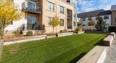 grassy area surrounded by benches outside an apartment building