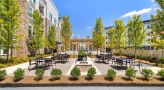 a courtyard with tables and chairs and trees and buildings in the background