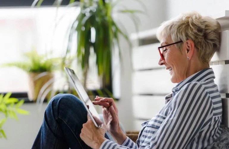 A senior adult woman on her tablet while sitting in her home.