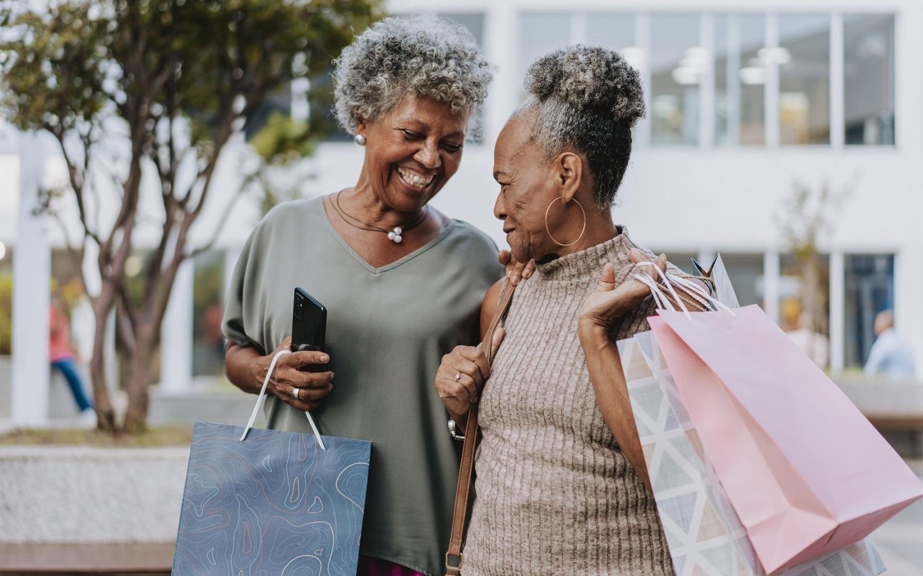 a couple of women smiling and holding shopping bags