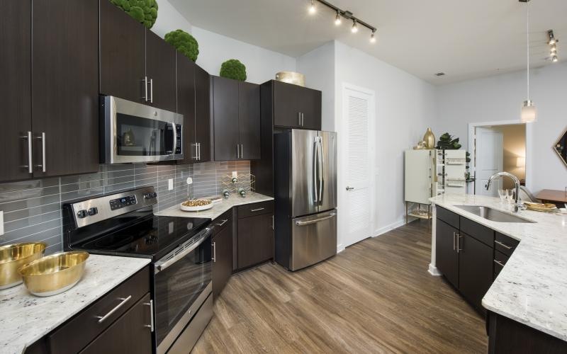 Spacious and well lit kitchen with wood floors and stainless steel appliances