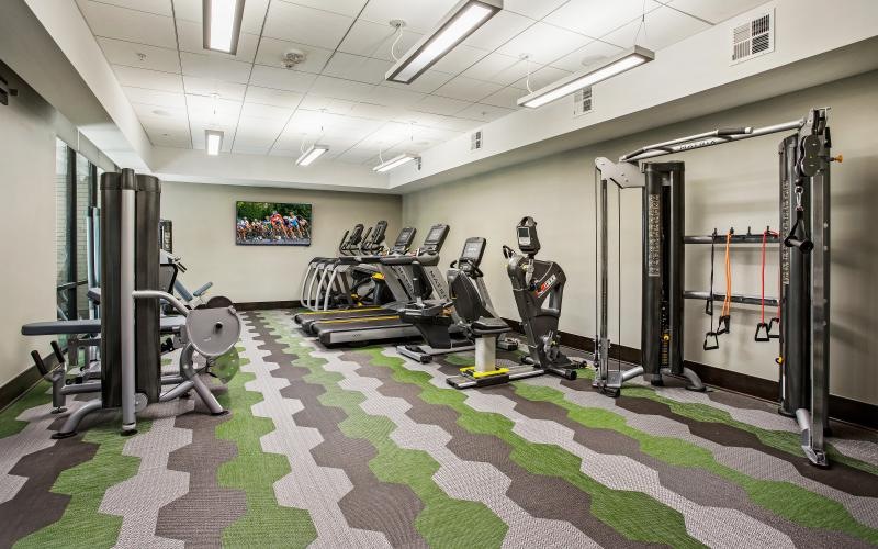 Large fitness center with ample machines and wood floors