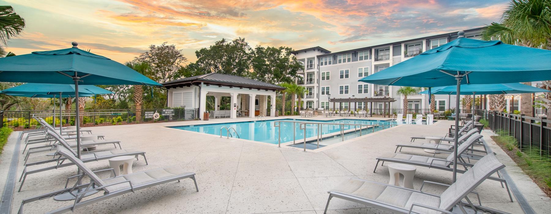 a pool with umbrella shaded lounge chairs