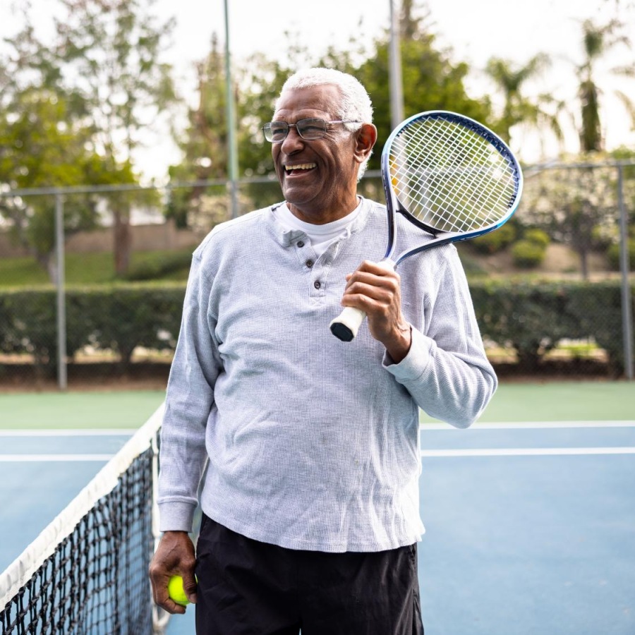 Your Wellness is Our Reason for Being guy smiling on a tennis court