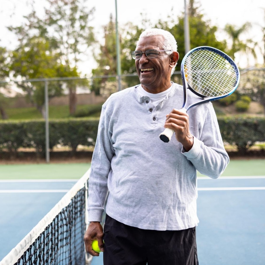Your Wellness is Our Reason for Being guy smiling on a tennis court