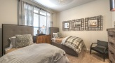 Large well lit bedroom with carpeted floors and a large window 