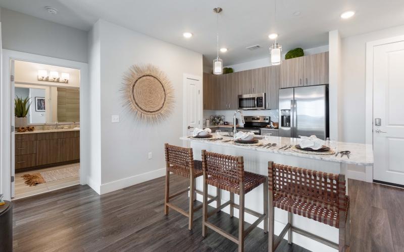 Spacious and well lit kitchen with wood floors and stainless steel appliances