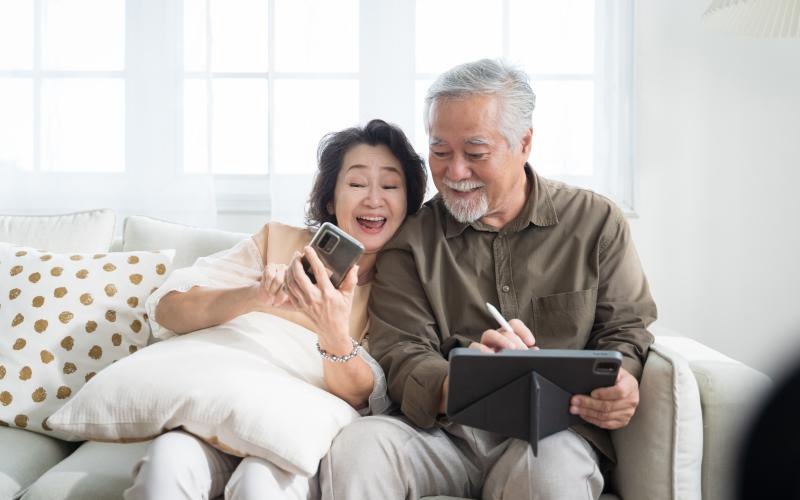 a man and a woman sitting on a couch looking at a phone