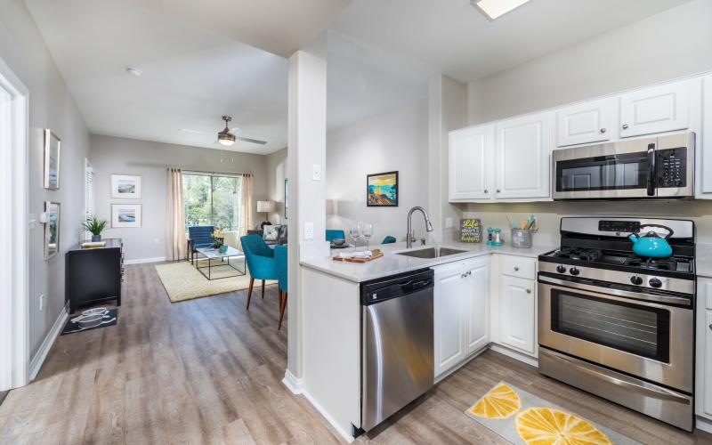 Spacious and well lit kitchen with wood floors and stainless steel appliances