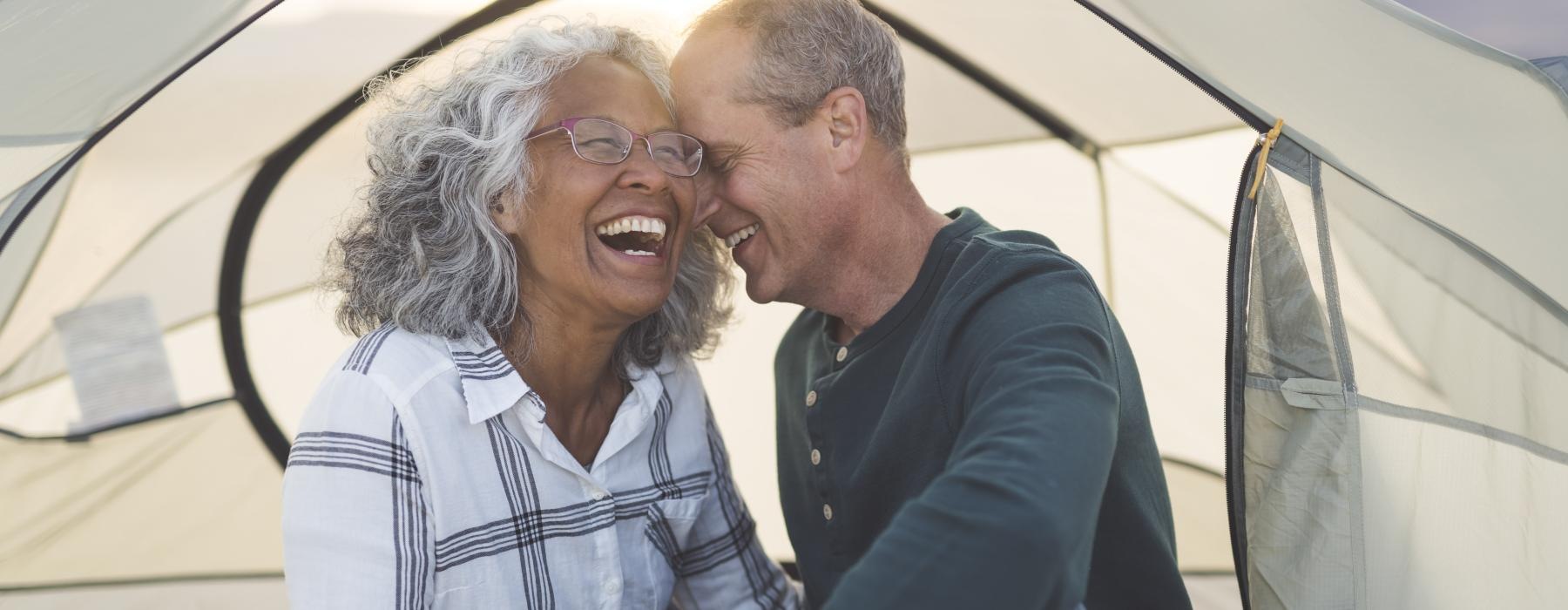 Couple laughing while relaxing in a tent