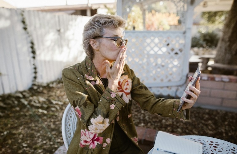 a woman looking into her cell phone blowing a kiss