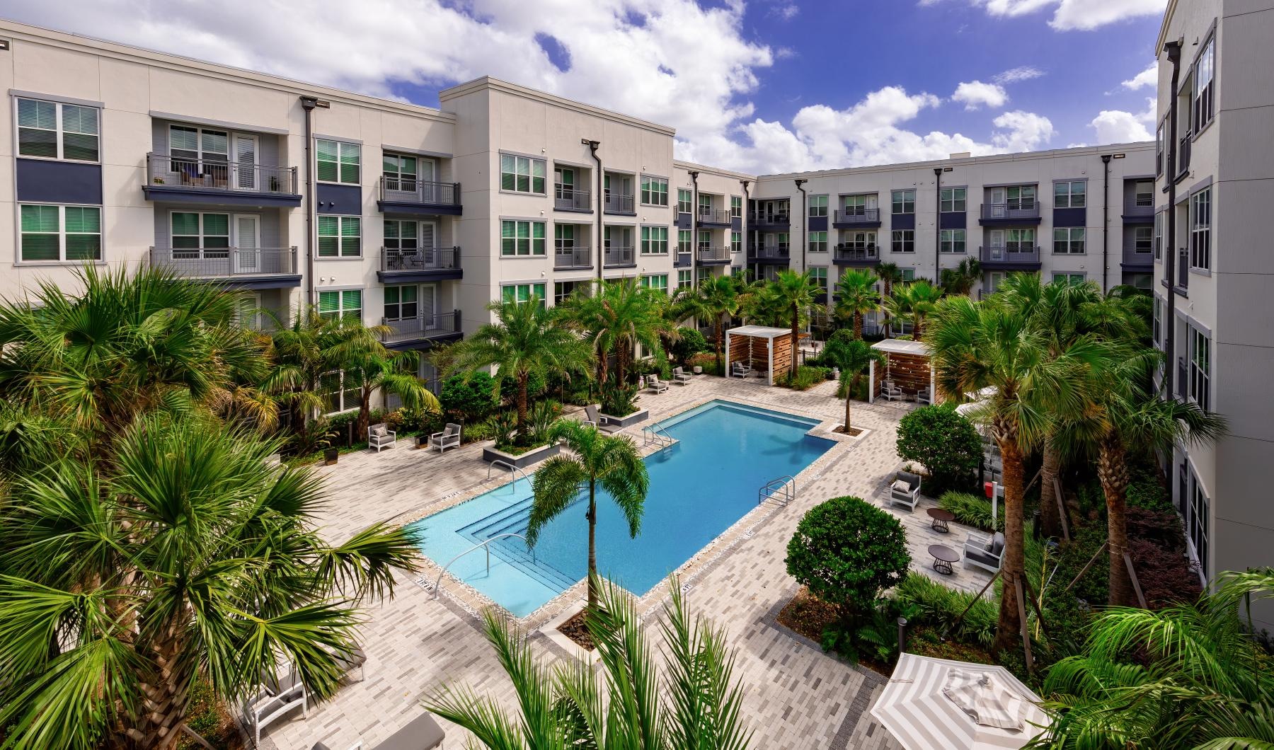 Large sparkling blue pool with a large deck and lounge chairs 