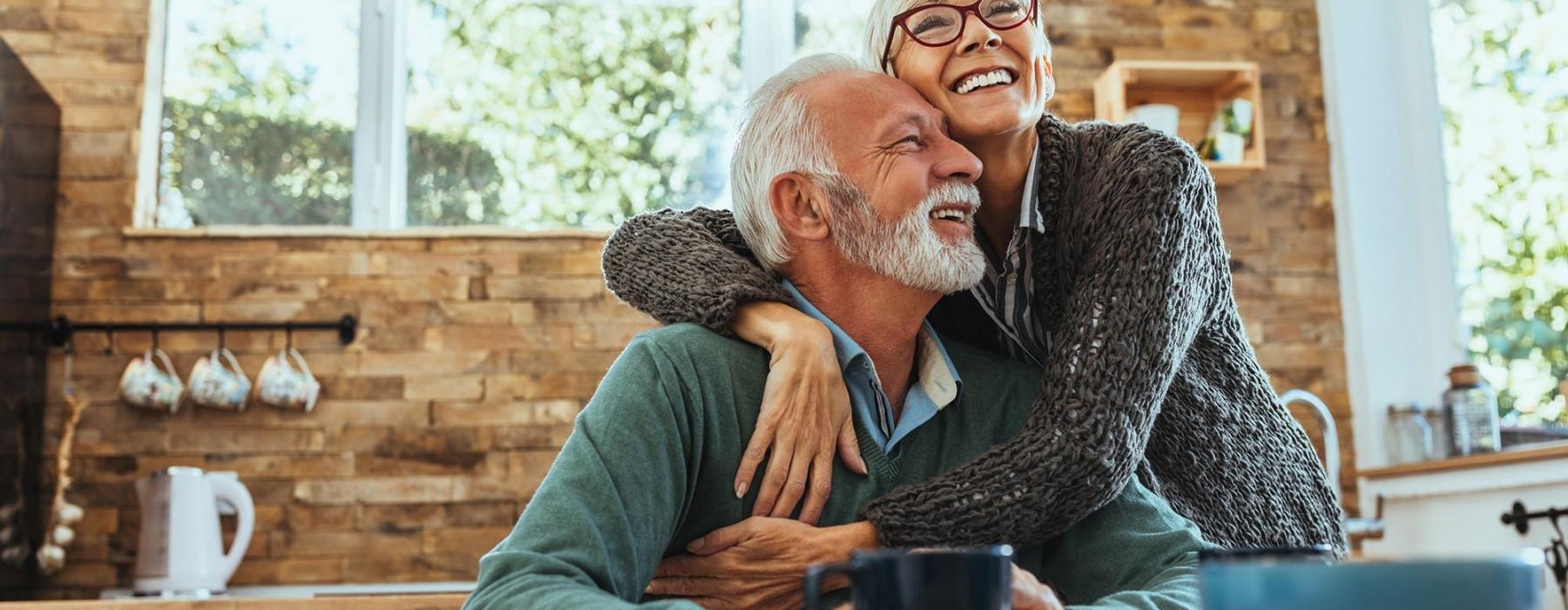 older couple hugging in their sun-filled kitchen