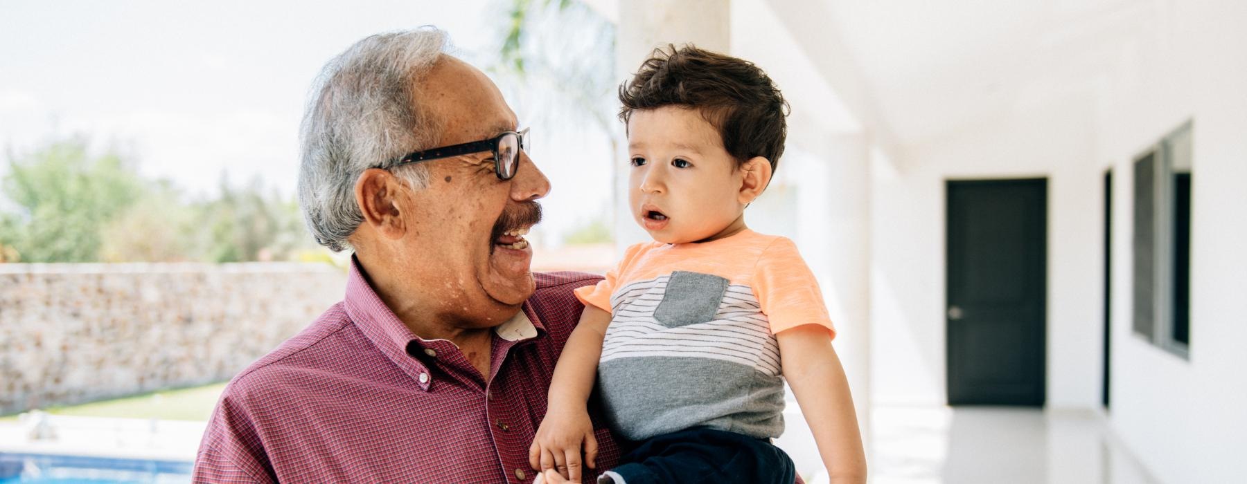 grandfather holding his grandson near a pool