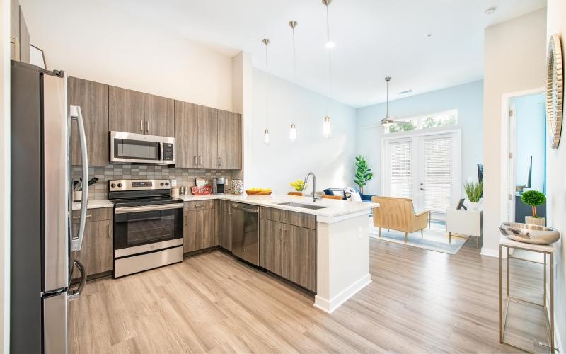 Spacious and well lit kitchen with wood floors and stainless steel appliances