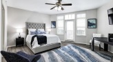 Large well lit bedroom with carpeted floors and a large window 