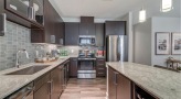 Spacious and well lit kitchen with stainless steel appliances and dark accents 