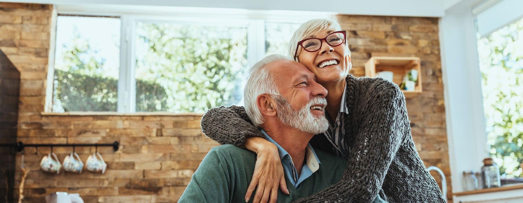 older couple hugging in their sun-filled kitchen