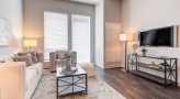 Spacious and well lit living room with wood floors and a large window