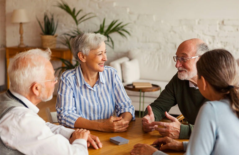 Group of senior adults playing card games and socializing around a table.