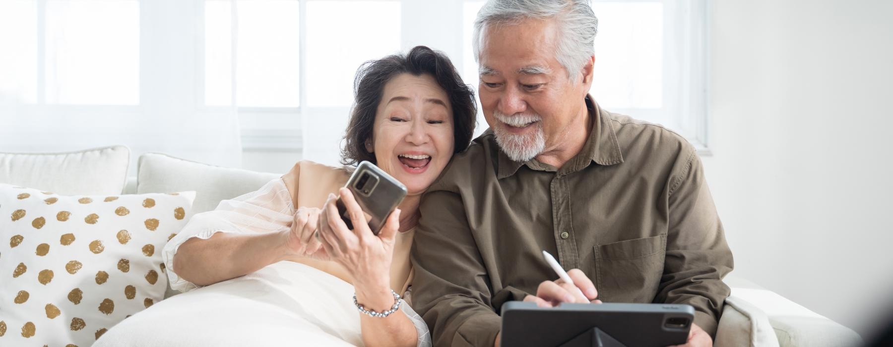 Couple sitting in their living room smiling at their phone