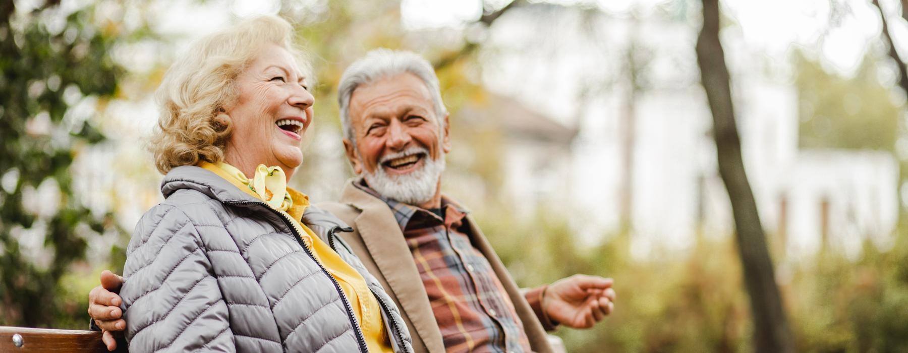 a man and woman sitting on a park bench, laughing together