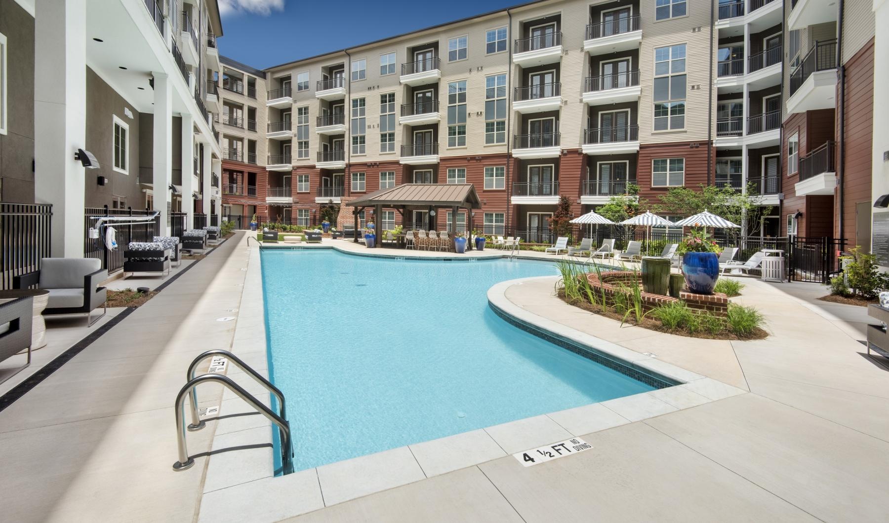 Large sparkling blue pool with a large deck and lounge chairs 