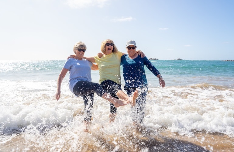 three people at beach splashing in the water