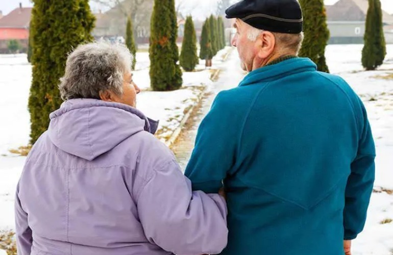 A senior adult couple go for a walk in the winter.