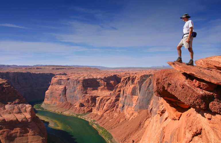 A hiker standing on top of a overlook of a canyon.