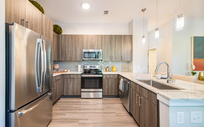 Spacious and well lit kitchen with wood floors and stainless steel appliances