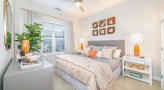 Large well lit bedroom with carpeted floors and a large window 