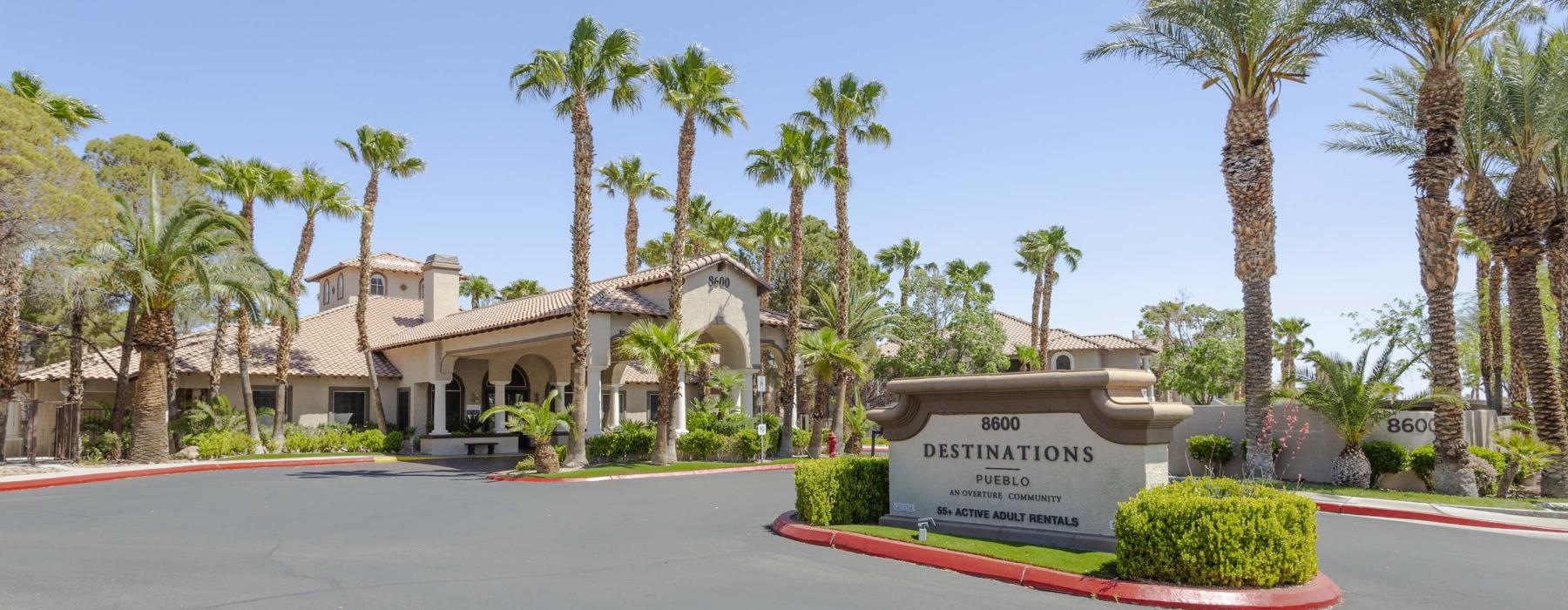 a sign leading into a parking lot with palm trees