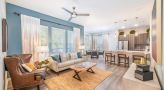 Spacious and well lit living room with wood floors and a large window