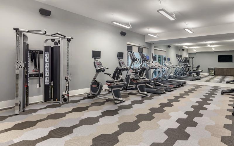 Large fitness center with ample machines and wood floors