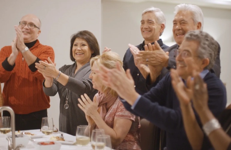 A group of senior adults clapping around a dinner table.