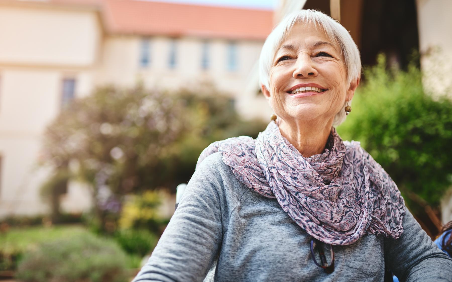 Lifestyle Resident walking outside and smiling at Overture Yorktown 55 and older apartments in Lombard, Illinois.