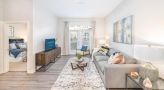 Spacious and well lit living room with wood floors and a large window