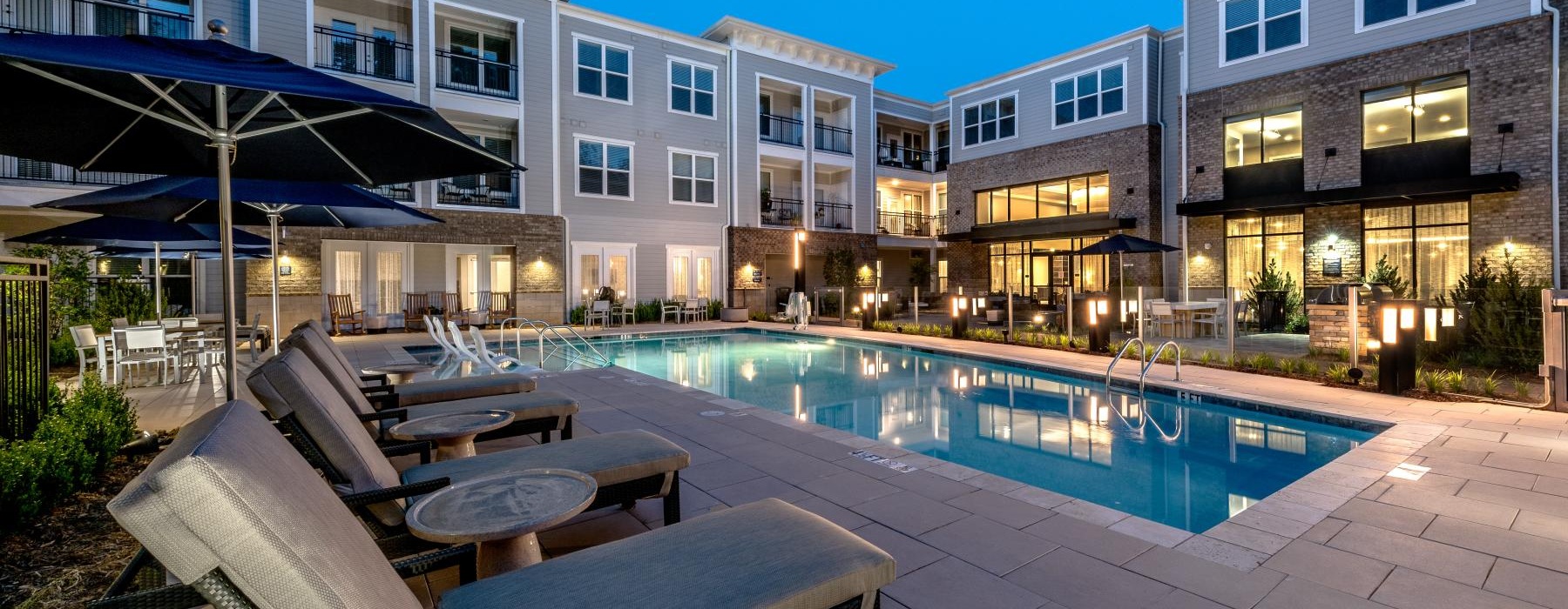 a swimming pool with lounge chairs and umbrellas next to it