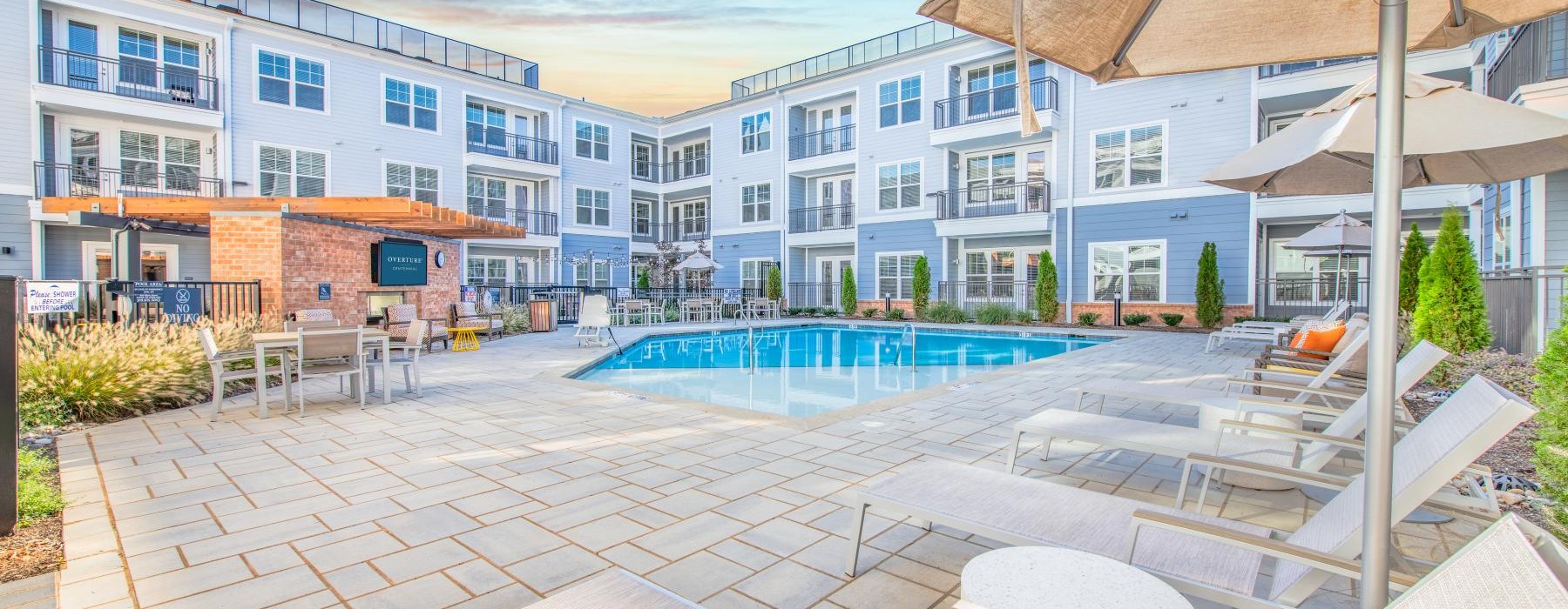 Large sparkling blue pool with a large deck and lounge chairs 