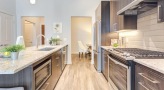 Spacious and well lit kitchen with stainless steel appliances and dark accents 