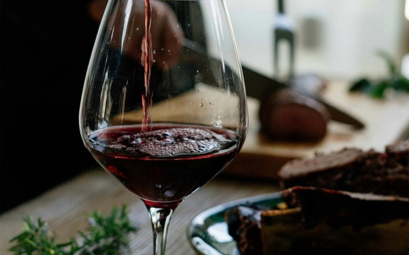 Thoughtful details to elevate your lifestyle A glass of red wine being poured at Destinations Pueblo apartments in Summerlin, NV, featuring a dining table.