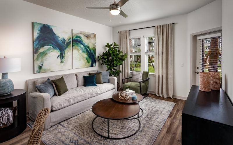 Spacious and well lit living room with wood floors and large windows 