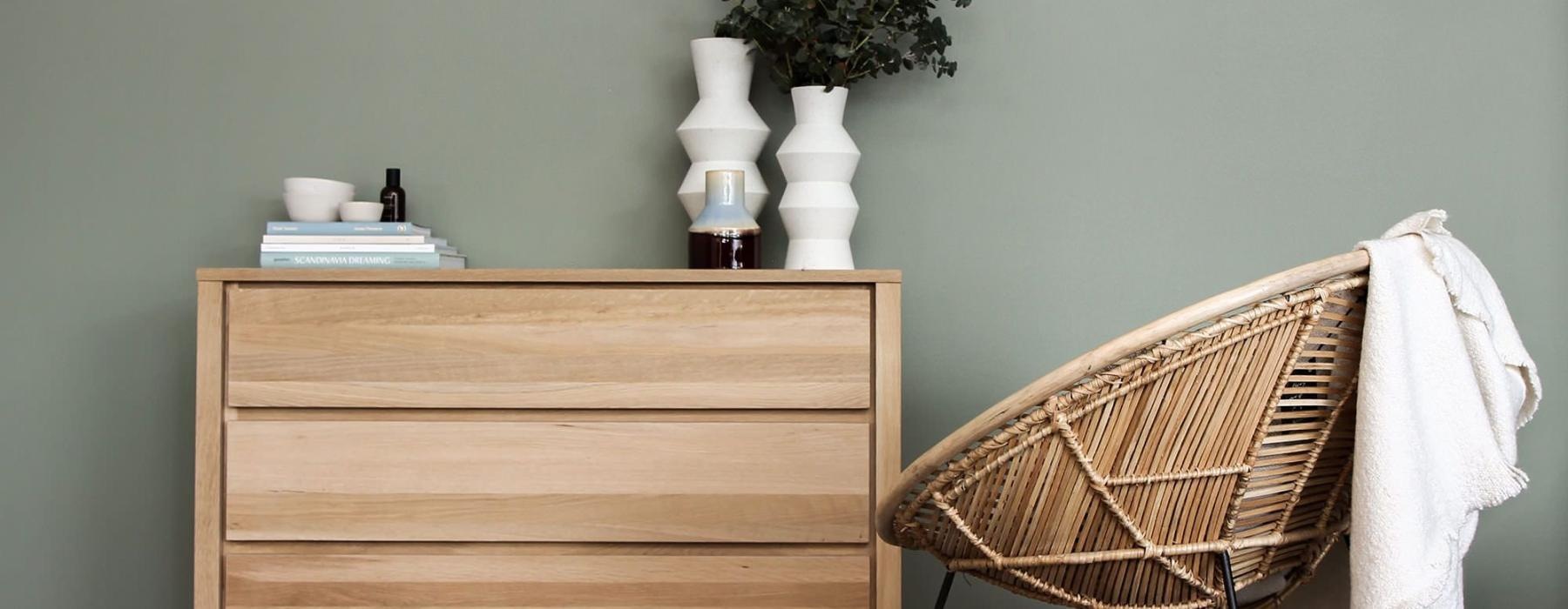 decor on a tall, wooden dresser next to a papasan chair with a throw